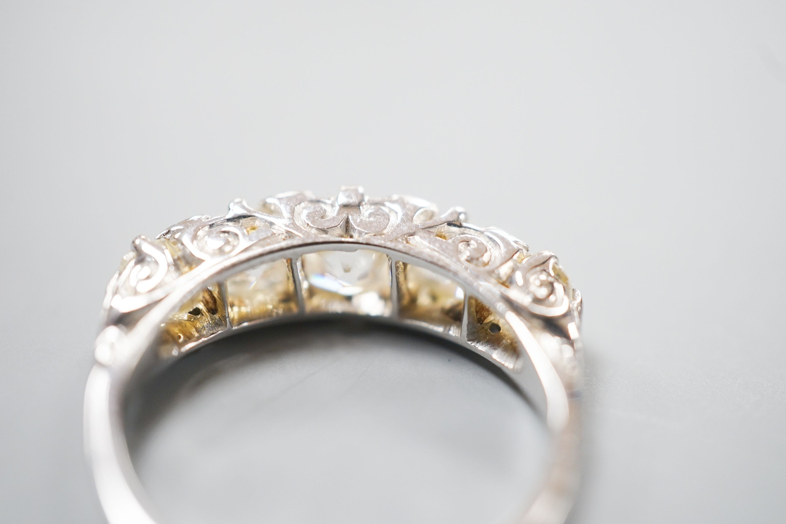 A white metal and graduated five stone old cut diamond set half hoop ring, with diamond chip spacers, size L, gross weight 3.7 grams.